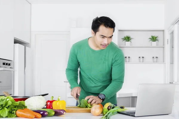 Hombre joven buscando receta en el ordenador portátil — Foto de Stock
