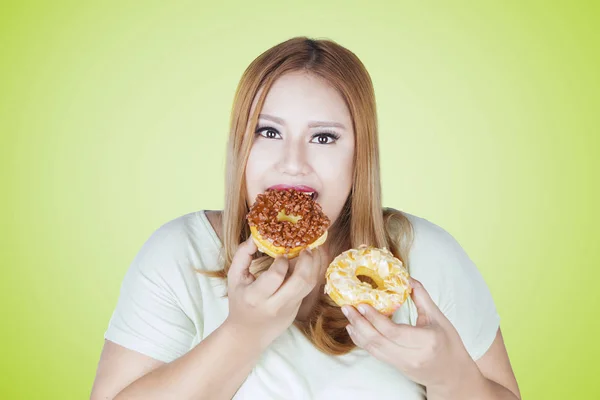 뚱뚱한 여자 두 개의 도너츠를 먹으십시오 — 스톡 사진