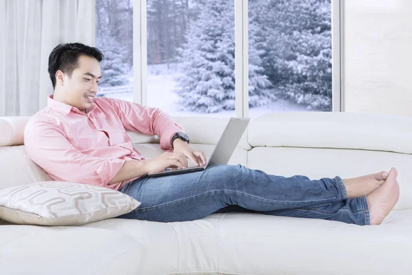 Homem digitando com laptop no sofá — Fotografia de Stock