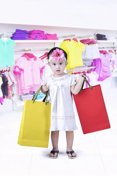 Söt flicka håller papperspåsar på mall — Stockfoto