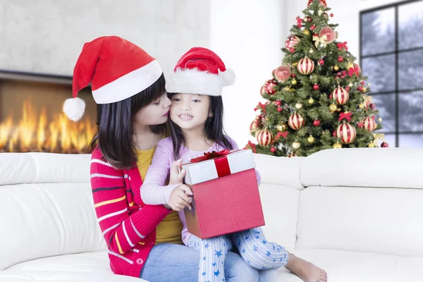 Bella madre bacia bambina con regalo — Foto Stock