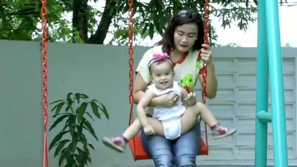 Jonge moeder en kind spelen op schommel — Stockvideo