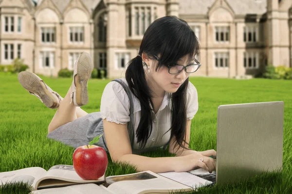 Aziatische schoolmeisje gebruikt laptop op veld — Stockfoto