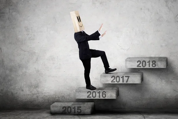 Businessman with cardboard head steps on stairs — Stock Photo, Image