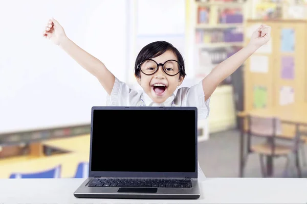 Ребенок празднует победу с ноутбуком в классе — стоковое фото