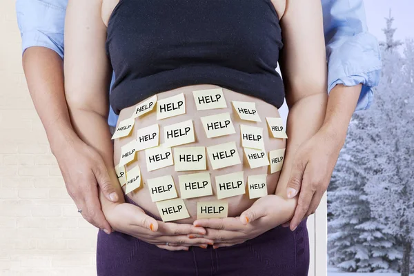 Couple holding belly with help text — Stock Photo, Image