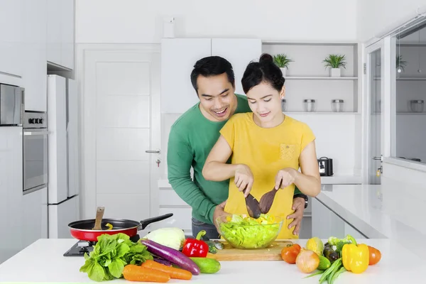 Mann schaut seine Frau an und macht Salat — Stockfoto