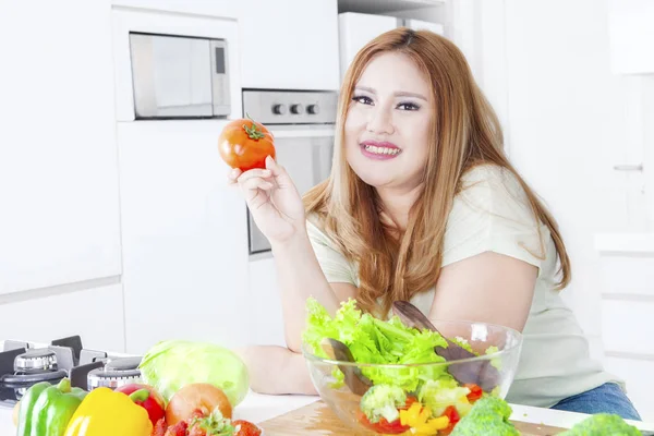 太りすぎの金髪女性はトマトを保持します。 — ストック写真