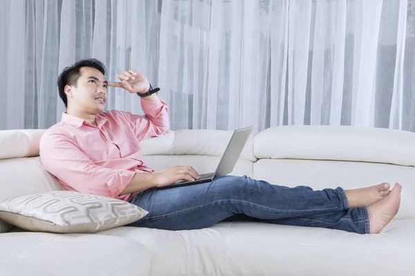 Nachdenklicher Mann mit Laptop auf der Couch — Stockfoto