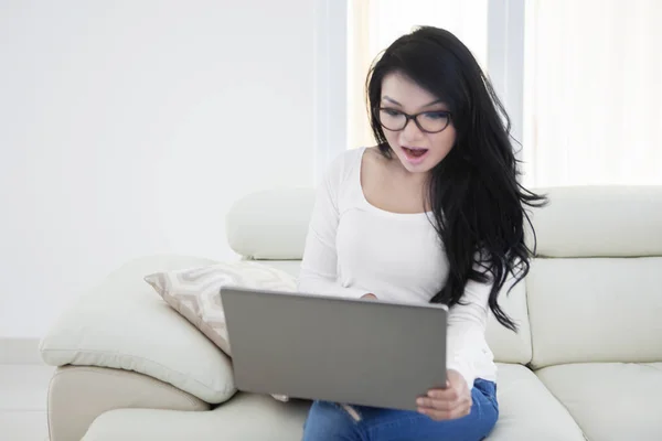 Mulher com cabelos longos usa laptop no sofá — Fotografia de Stock