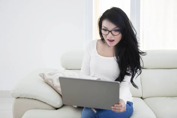 Woman with long hair uses laptop on sofa — Stock Photo, Image