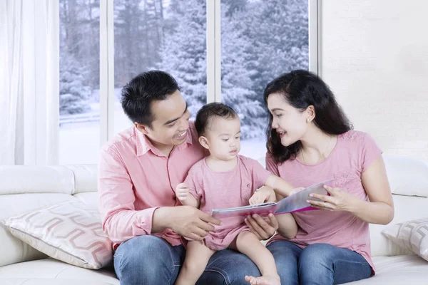 Junge Familie liest Bilderbuch auf Couch — Stockfoto