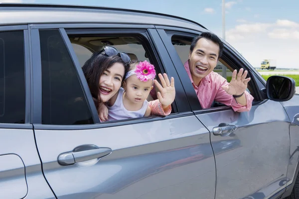 Familia joven saludando las manos en el coche — Foto de Stock