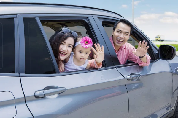 Jovem família acenando as mãos no carro — Fotografia de Stock