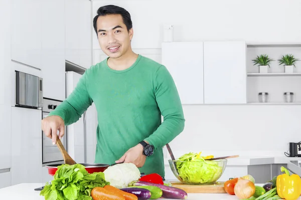 Ung man matlagning grönsaker — Stockfoto