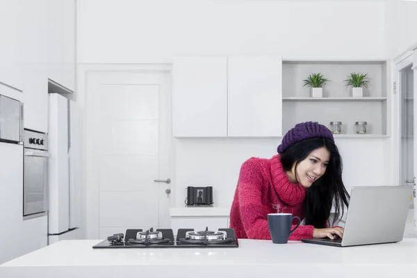 Jonge vrouw met laptop in de keuken — Stockfoto