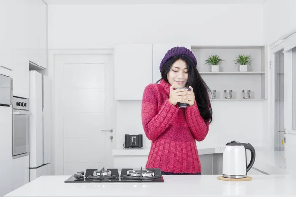 Mujer joven con bebida caliente en la cocina — Foto de Stock