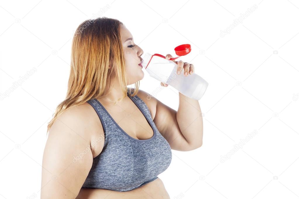 Overweight woman drinks water after workout 