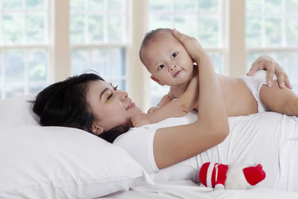 Gladlynt kvinna leker med barnet på säng — Stockfoto