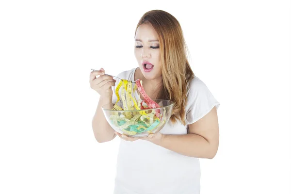 Толстая женщина ест измерительные ленты — стоковое фото