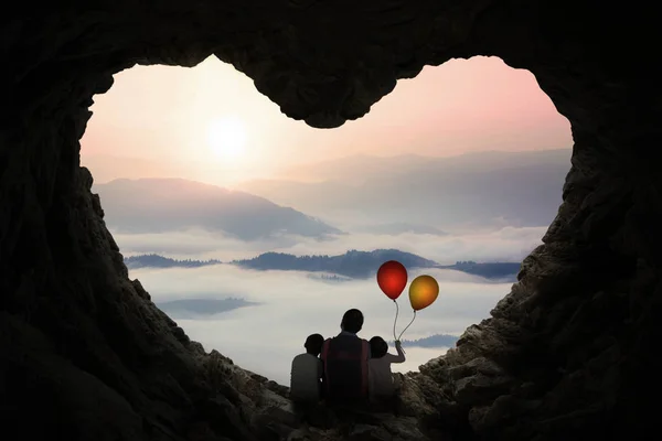 Pai e crianças desfrutam de vista montanha na caverna — Fotografia de Stock