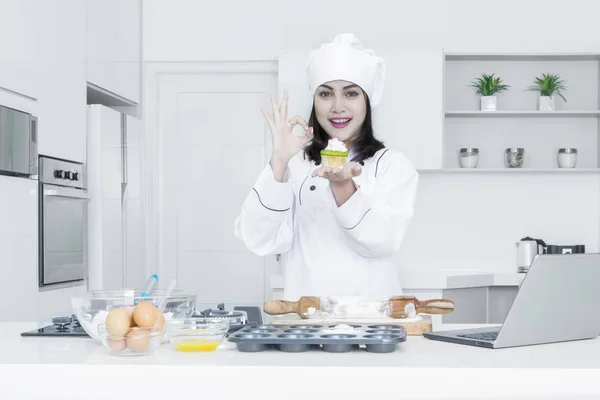 Chef feminino segura cupcake na cozinha — Fotografia de Stock