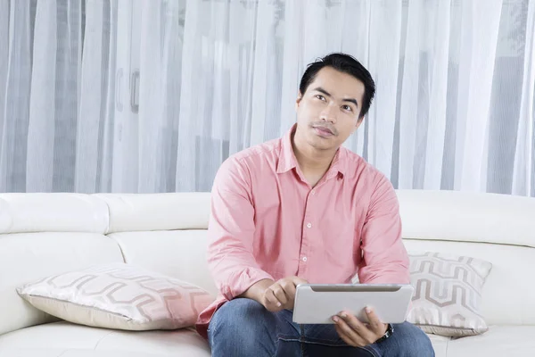 Handsome man using tablet on couch — Stock Photo, Image