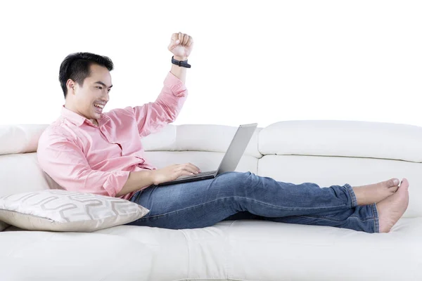 Šťastný muž pomocí přenosného počítače na gauči — Stock fotografie