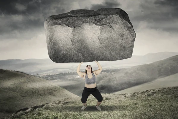 Fettleibige Frau hebt Stein in Hügeln — Stockfoto