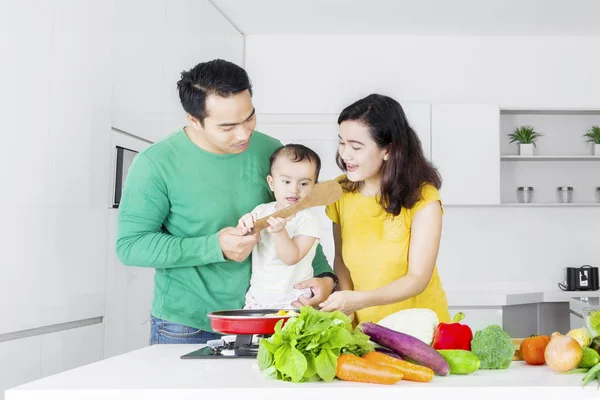 Två föräldrar och dotter matlagning grönsaker — Stockfoto