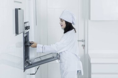 Genç baker fırın tepsi fırına koyar.