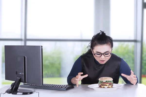 Молода бізнес-леді дивиться гамбургер — стокове фото