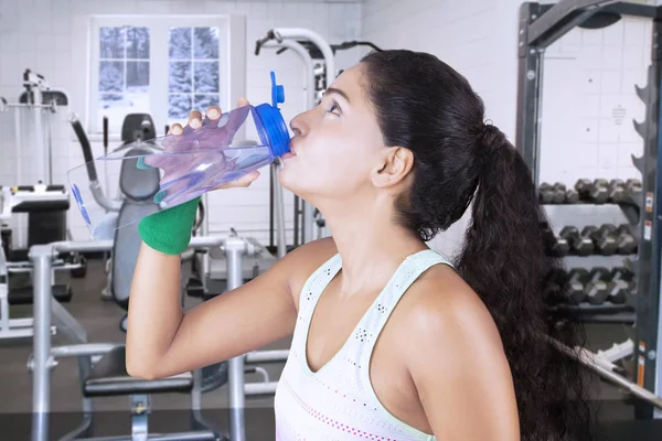 Young woman drinks water in fitness center — Stock Photo, Image