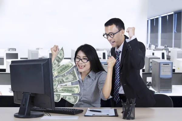 Trabajadores jóvenes con dinero en monitor — Foto de Stock