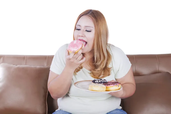Kobieta blonde zjada pączki na kanapie — Zdjęcie stockowe