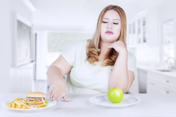 Mujer rubia rechaza hamburguesa en la cocina — Foto de Stock