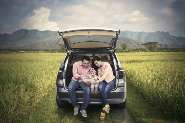 Семья сидит за машиной на рисовом поле — стоковое фото