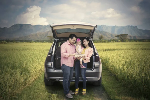 Família em pé no campo de arroz com comprimido — Fotografia de Stock