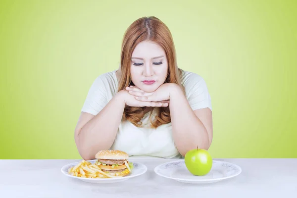 Vrouw denkt om te kiezen van apple of Hamburger — Stockfoto