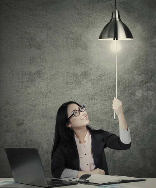 Businesswoman switching on idea light bulb — Stock Photo, Image