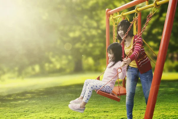 Dochter en moeder spelen swing in park — Stockfoto