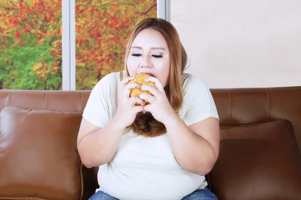 Mujer gorda parece hambrienta en el sofá —  Fotos de Stock