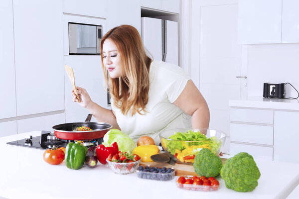 Fat woman sniffing meal on frying pan