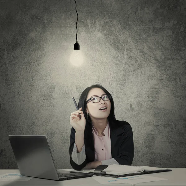 Female entrepreneur thinking under a light bulb — Stock Photo, Image