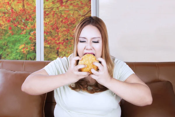 Жадная толстая женщина, наслаждающаяся гамбургером — стоковое фото