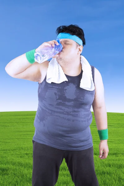 El hombre obeso está bebiendo en el prado — Foto de Stock