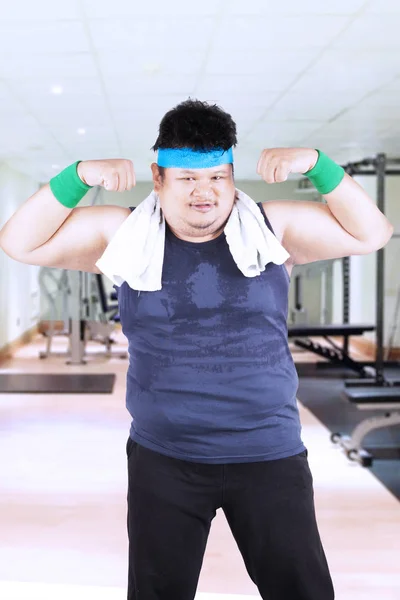 Obese man showing strong arms at the gym — Stock Photo, Image