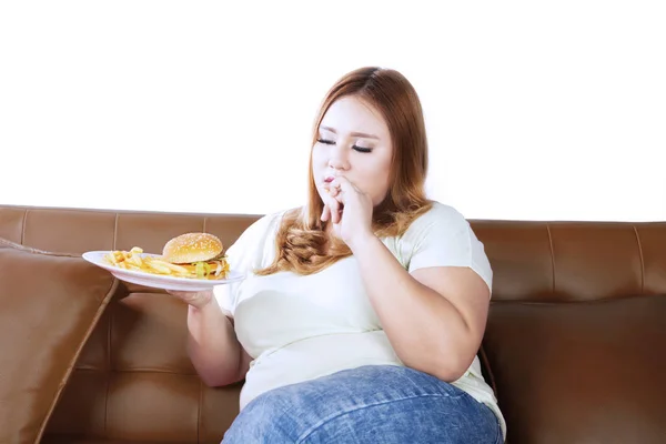 Толстая женщина ест нездоровую пищу — стоковое фото