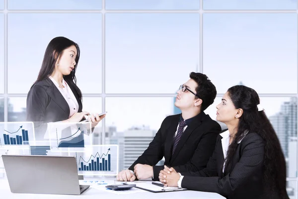 Mujer y socios discutiendo gráfico financiero — Foto de Stock