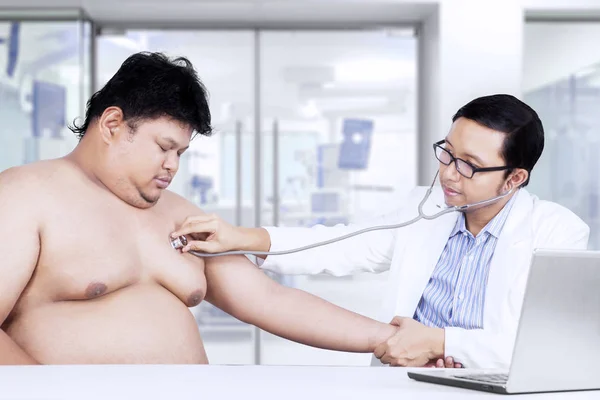 Asian doctor listens patient heartbeat — Stock Photo, Image